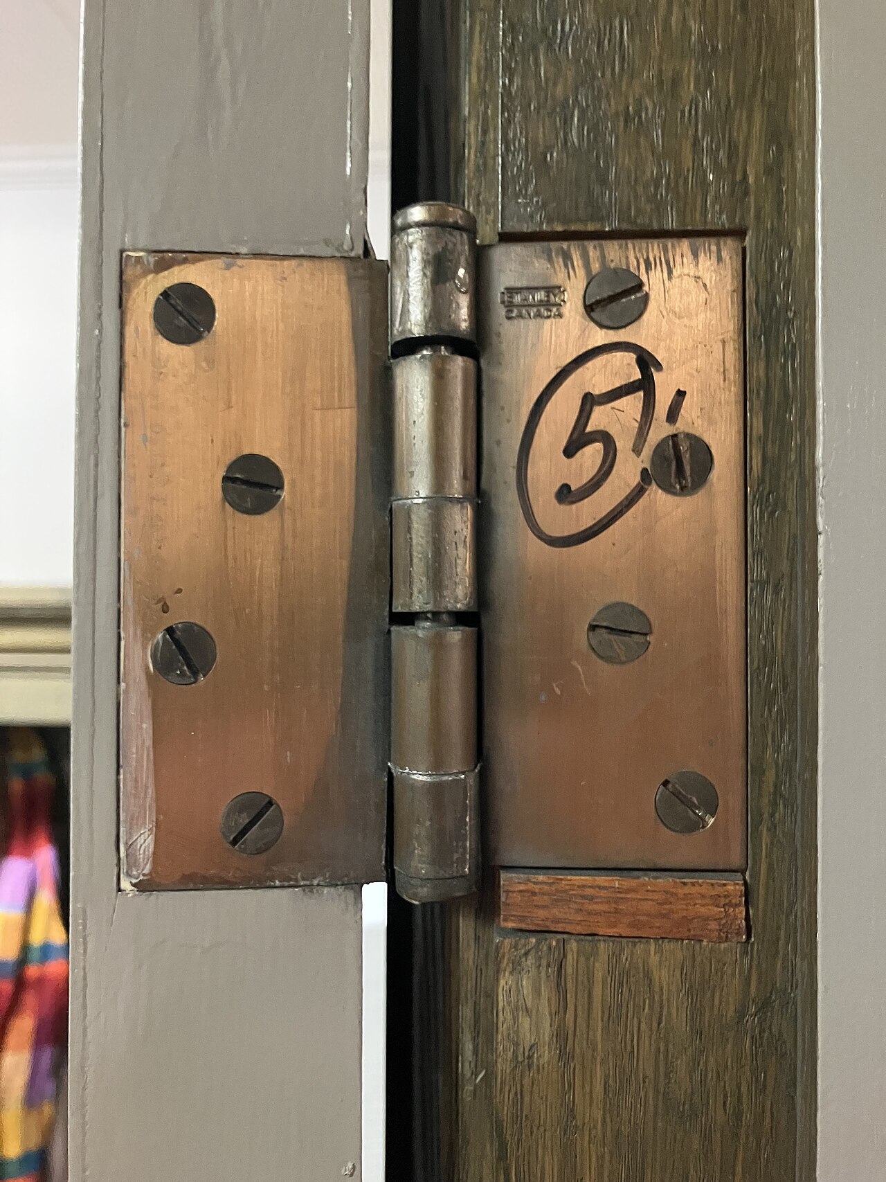 Dobradiça de porta vista de perto, mostrando os parafusos de fixação