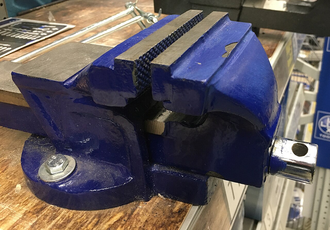 Morsa de bancada de ferro fundido em exposição, mostrando as mandíbulas estriadas