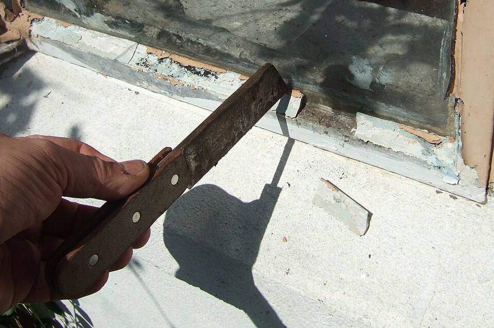 Faca de vidraceiro (hacking knife) removendo massa velha de uma janela antes da reaplicação