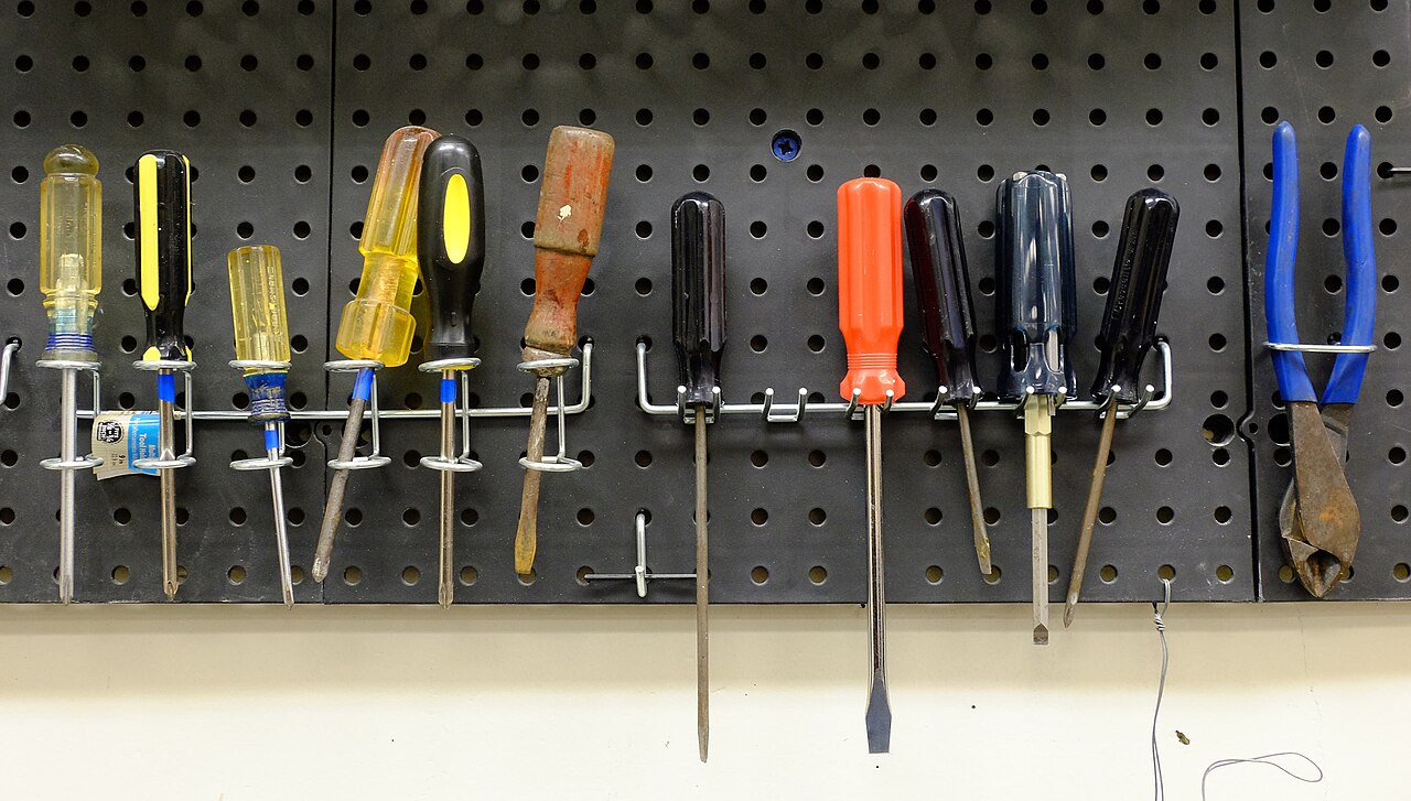 Painel pegboard com chaves de fenda organizadas em ganchos acima da bancada