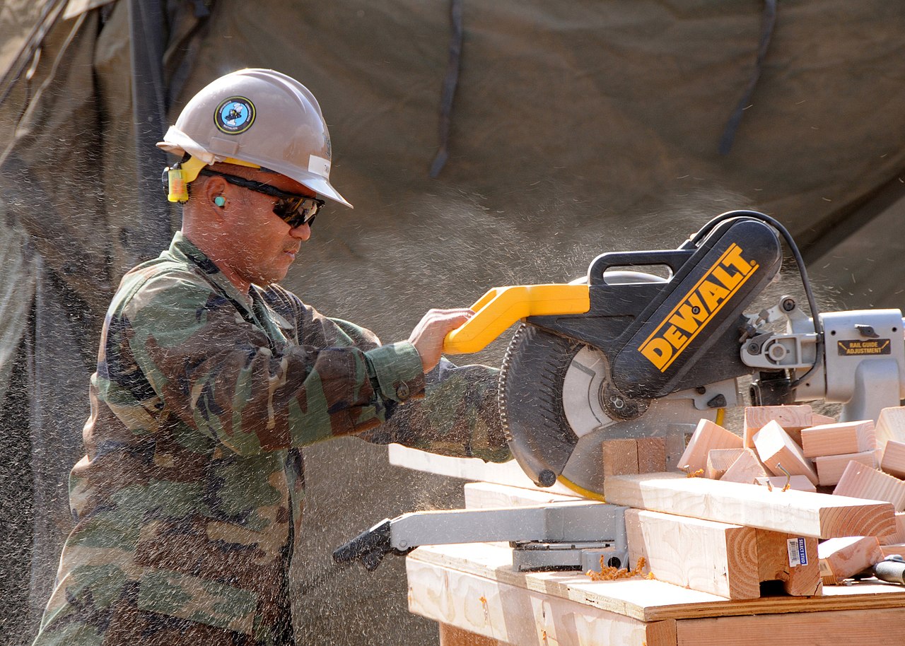 Trabalhador usando serra de esquadria para cortar madeira com equipamento de proteção