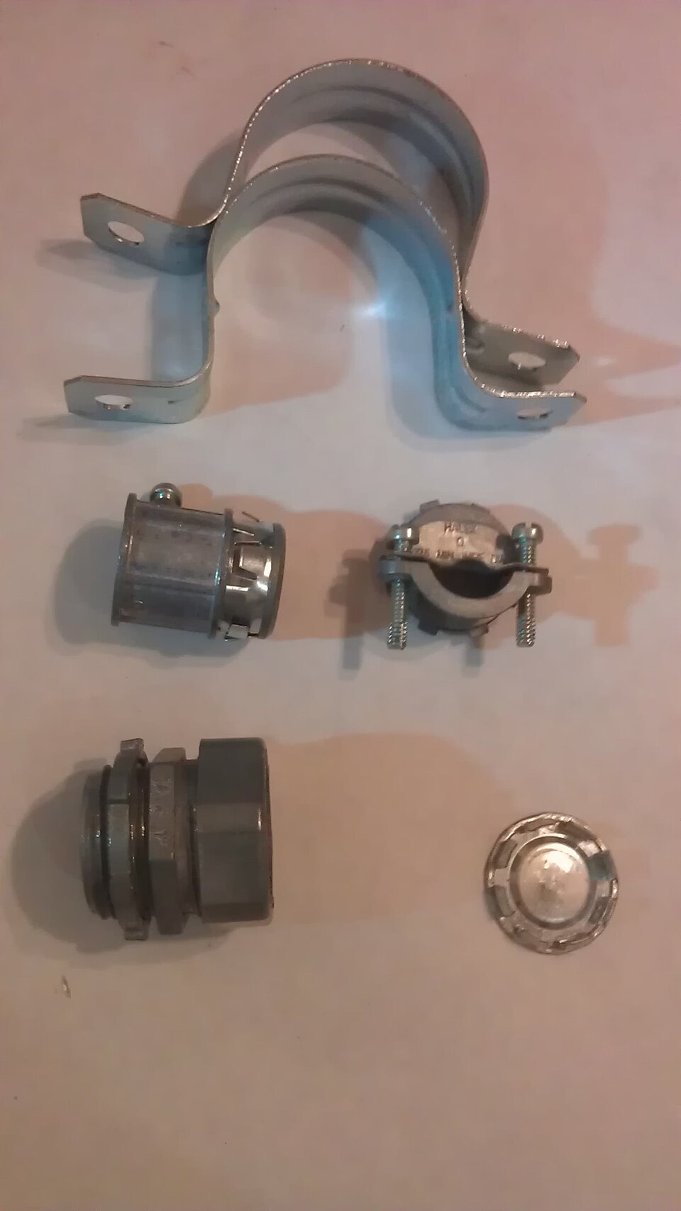 Conectores, abraçadeiras e luvas metálicas usados na transição entre trechos de eletroduto