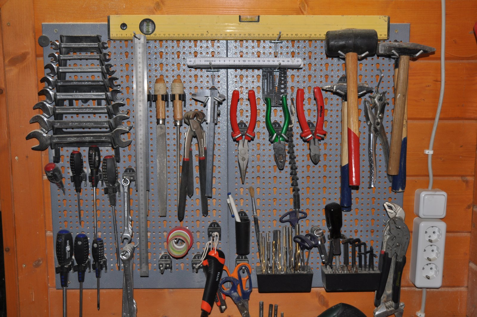 Painel de parede perfurado (pegboard) organizando ferramentas manuais