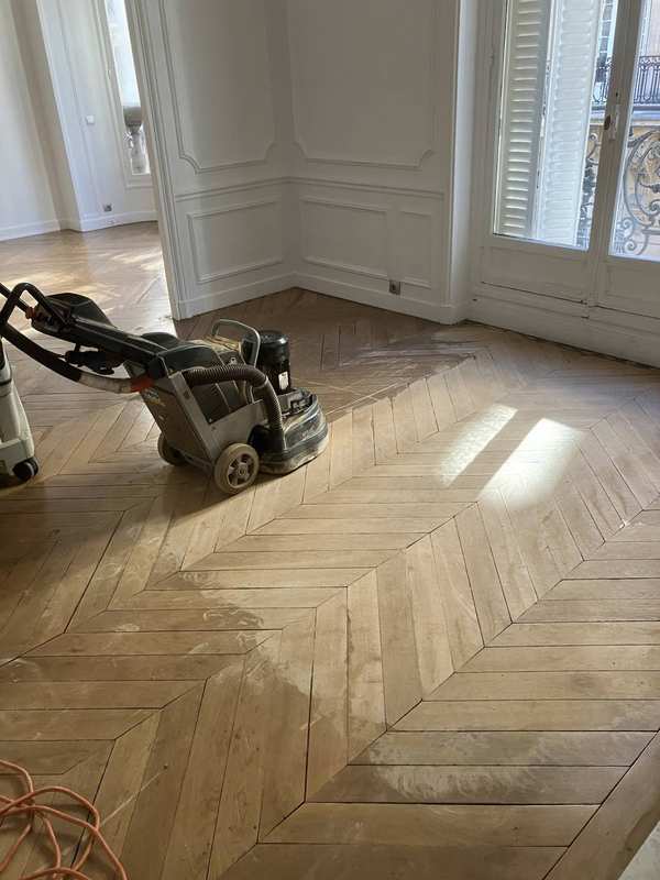 Profissional lixando piso de madeira (parquet) com máquina de lixar elétrica