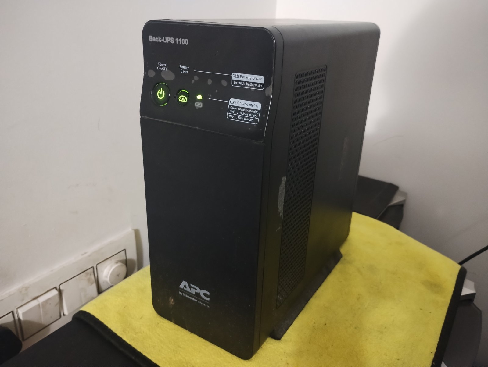 Nobreak residencial compacto (UPS) sobre uma mesa, com botão de ligar e indicadores de carga da bateria