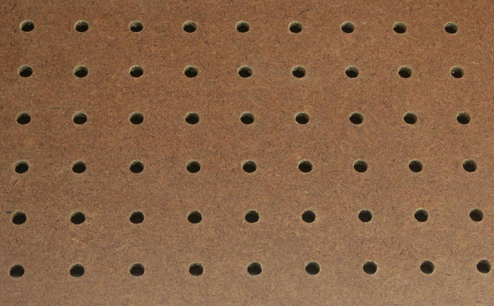 Detalhe da superfície de um painel pegboard perfurado em MDF, com furos regulares