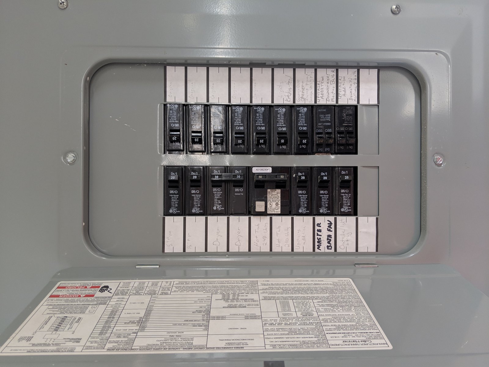Quadro de disjuntores elétricos residenciais com a tampa aberta, mostrando a fileira de disjuntores