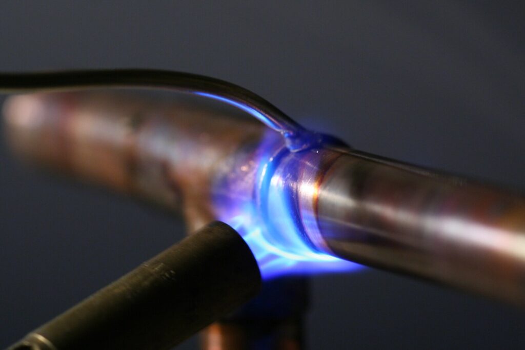 Chama azul de macarico a gas soldando junta de cano de cobre com solda de estanho