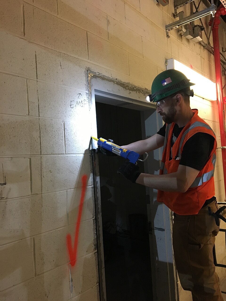 Trabalhador aplicando silicone com pistola de aplicação profissional em um batente de porta