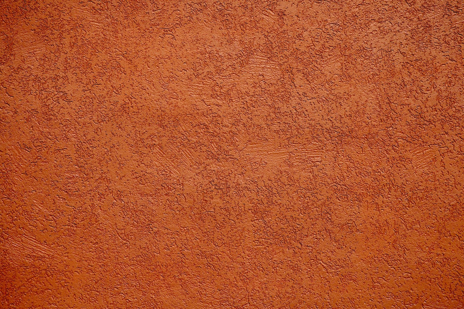Parede externa com acabamento em textura rústica de estuque, mostrando o relevo irregular típico desse tipo de revestimento