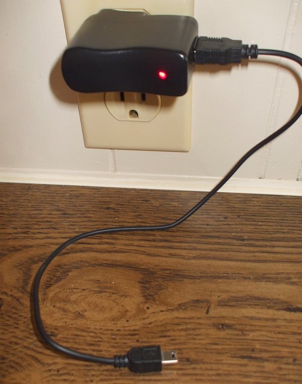 Adaptador USB plugado diretamente em uma tomada de parede, com fio solto até o aparelho