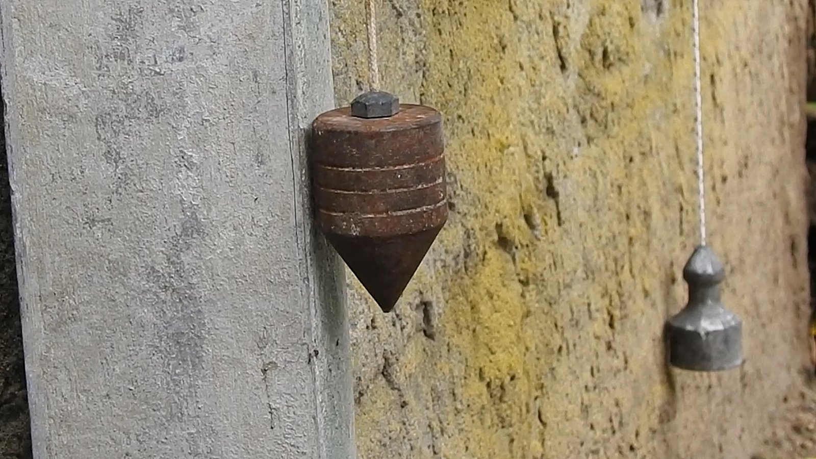 Uso do prumo de pedreiro para verificar a verticalidade de uma parede em alvenaria